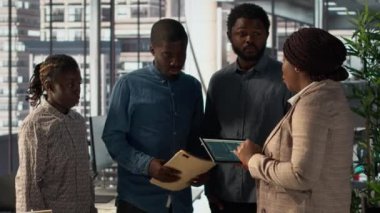 Afrika kökenli Amerikalı yönetici, üst düzey bir ofiste çalışanlarıyla şirket stratejisini inceliyor ve şirket gelişimini desteklemek için önemli iş kararları alıyor. Kaynak tahsisi oluşturun. Kamera A.