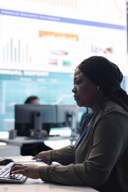 Büyük ekranlı bir monitör odasında bilgisayardaki bilgi grafikleri üzerine çalışan pazarlama uzmanı yıllık veri raporlarından müşteri memnuniyetini kontrol eder. Çalışanların performans ölçümleri.