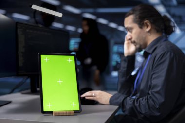 Veritabanlarını yönetmek için kullanılan sunucuları denetlemek için bulanık arkaplanda geliştirici tarafından kullanılan izole ekran tabletine odaklan. Bilgi Merkezi 'nde bilişim uzmanı tarafından kullanılan kroma anahtarının yakın çekim görüntüsü