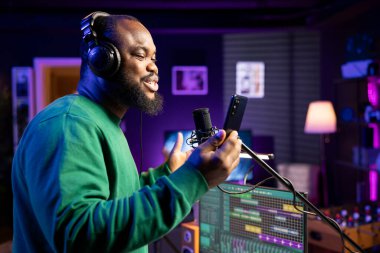 Yetenekli bir sanatçı, akustik seansından önce yeni şarkısını kaydediyor ve stereo teçhizatla kendi stüdyosunda bir soundtrack yapıyor. Genç müzisyen mikrofonda bir melodi çalıyor..