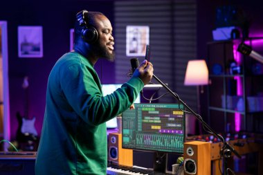 Genç müzisyen söz yazarı şarkısının akustik versiyonunu kaydediyor, mikrofondan canlı performans sergiliyor. Yetenekli besteci, yaratıcı şarkı sözleriyle yeni ezgiler üretiyor..