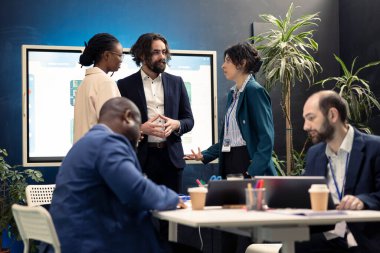 Bir şirket toplantısında yeni projenin iç yüzünü tartışan bir iş kuruluşunun takım üyeleri. Çeşitli iş arkadaşları sanayi gelişmeleri ve yasal kararnameler hakkında bilgilendiriliyor.