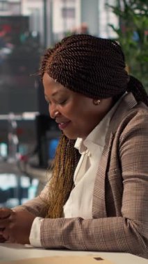 Dikey Video Siyah işletme çalışanı, sosyal medya sitelerine girip ofisteki birkaç mesaja cevap veriyor. Kadın işçi mesajlaşma yoluyla çevrimiçi iletişim kuruyor. Kamera.