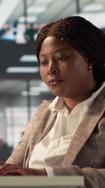 Ofis masasındaki dikey video özgüveni olan iş kadını rapor yazma ve cevap yazma, idari işler yönetimi üzerinde çalışıyor. Siyahi kadın uzman başarıyı garanti altına almak için hedefleri gözden geçiriyor