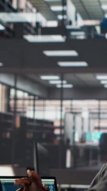 Dikey Afrikalı Amerikalı çalışan ofiste kollarını ve sırt kaslarını esnetiyor idari bir görevi bitirdikten sonra sandalyesinde dinleniyor. Erkek analist hedeflerini belirliyor