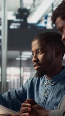 Dikey Video İş Yöneticisi, PC 'deki finansal tahminleri gözden geçirmek için bir işçiyle birlikte oturuyor ve proje geliştirme hakkında bir analitik değerlendirmeye öncülük ediyor. Gelişim için organizasyonel hedeflere ulaşmak. Kamera A.