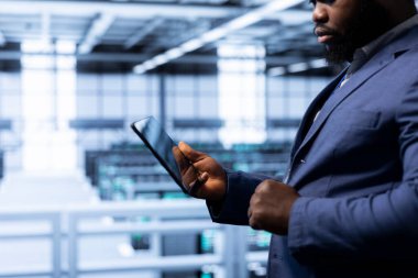 Yüksek teknoloji veri merkezinde tablet kullanan veri araştırmacısı, siber güvenlik ve etkin ağ yönetimi sağlıyor. Sunucu merkezinde çalışan aygıtla veri merkezi donanımını optimize ediyor