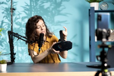 Gözlemci yüksek teknoloji VR kulaklığı hakkında izleyicilerle konuşuyor. Görüntüleri yakalamak için akıllı telefon kullanıyor. Derede hayranlarıyla sohbet eden, telefonla sanal gerçeklik gözlüklerini çeken bir kadın.