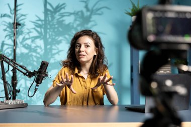 Yüksek teknolojili mikrofon ve özel çekim teçhizatıyla ASMR yaratıcısı rahat ev stüdyosunda stres önleyici video yapıyor. Aboneler için rahatlatıcı içerik için profesyonel mikrofon ve kamera kullanan kadın