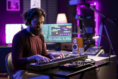 Piyano klavyesi çalan ve karışık ve ana oturum için müzik kaydeden şarkı yazarı, yeni şarkılar yaratmak için daw yazılımını kullanıyor. Midi denetleyici ile müzik besteleyen ses üreticisi.