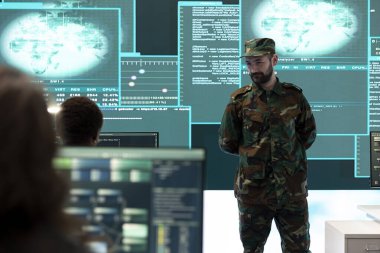 Hükümet ordu hackerları teşkilat ofisinde melez savaş stratejileri uyguluyor. Bilgi toplamak, saldırıları önlemek ve askeri operasyonları korumak için yazılım ve teknoloji kullanan personel.