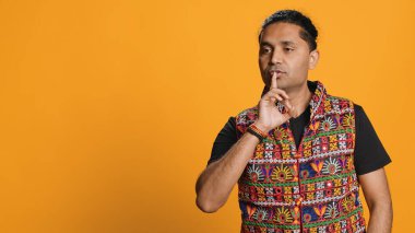 Sinirli Hintli adam el hareketi yapıyor. Gürültüden rahatsız olmuş, negatif ruh hali içinde. Parmağını dudaklara koyan, sessiz işaret hareketi yapan, stüdyo arka planı, kamera A