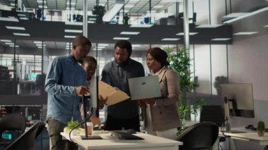 Afrikalı Amerikalı ekip, gelecekte şirket büyümesi için bilgilendirilmiş kararlar almak üzere takım çalışması ve veri analizini vurgulayarak bir iş alanında finansal planlama projesi üzerinde işbirliği yapmaktadır. Kamera B.