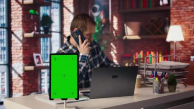 Chroma anahtar tableti ev ofisteki serbest çalışanın yanında dizüstü bilgisayarın önünde oturuyor, telefonlara cevap veriyor. Serbest çalışanın yanındaki izole ekran cihazı akıllı telefondan, kamera A 'dan telefon alıyor.