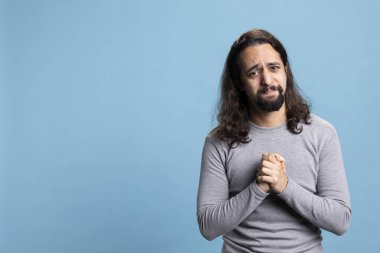 Bir duada el ele tutuşan ve İsa 'yla konuşan dindar kişi mavi arka plana karşı Hıristiyanlığa ve ruhaniliğe olan inancını gösteriyor. Uzun saçlı genç bir yetişkin af diliyor..