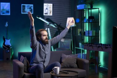 Coşkulu spor hayranları dairede canlı yayında en sevdikleri takımın kazanmasını kutlamak için el kaldırıyorlar. Dünya kupası futbol turnuvasında kendi ülke zaferinden zevk alan coşkulu bir adam.