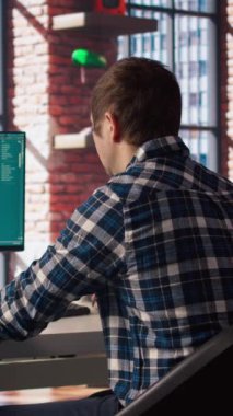 Adam modern şehir merkezindeki Al LLM sohbet robotu yazılımını kullanarak masada oturuyordu. Parlak apartman çalışma alanı, kamera A 'daki bilgisayardaki büyük dil model programından yardım isteniyor.