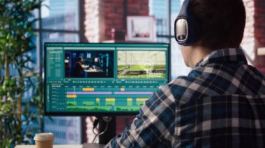 Video düzenleyici kulaklık takıyor, video montaj yapıyor, özel yazılım uygulaması kullanıyor, görüntüyü yakınlaştırıyor. Freelancer, PC üzerindeki düzenleme araçlarını kullanarak film projesinin görüntülerini ve kamera görüntülerini kesti.