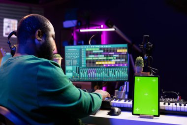 Sound engineer composing new tunes with daw interface, operating on greenscreen display. African american skilled musician mixing and mastering his recordings, stereo console and gear. clipart