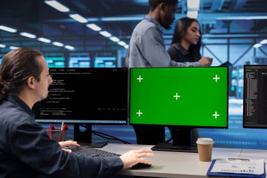 Veri merkezinde sunucu performans sorunlarını kontrol etmek için yeşil ekran bilgisayar kullanan programcı. Sunucu hub düzeltme hatalarında IT profesyoneli Mockup masaüstü PC kullanarak donanımı yavaşlatıyor