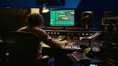 Müzik yapımcısı stüdyoda konsol ve ses yazılımlarını karıştırarak şarkıları düzenliyor, tuşlara basıyor ve kontrol odasındaki düğmeleri çeviriyor. Ses mühendisi melodi üretiyor ve sesi ayarlıyor. Kamera B.