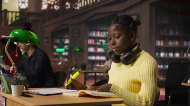 Kütüphanedeki genç kız çalışma oturumu için ilgili cümleleri vurguluyor, sınav için notlardaki paragrafları işaretliyor. Flüoresan bir kalemi çalışma tekniği olarak kullanmak. Kamera A.