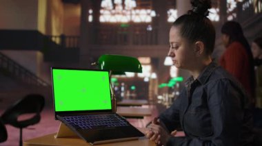 Bir halk kütüphanesinde dizüstü bilgisayarının yanında çalışan profesyonel kütüphaneci akademik kaynaklar ve rehberlik sağlıyor. Veritabanı içindeki eğitim bilgileri değerlendiriliyor. Kamera A.