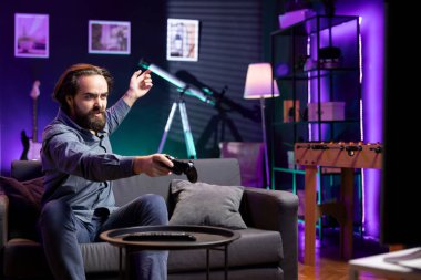 Oyuncu, SF video oyunu seviyesini kaybettikten sonra, öfkeli bir şekilde televizyona bağırıyor. Kızgın adam evde bağırıyor, TV ekranında maçı izledikten sonra sinirleniyor.