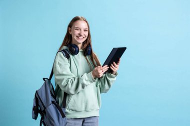 Tablet kullanan aşırı neşeli bir genç, eğlenceli sosyal medya paylaşımlarına gülüyor. Neşeli insan internet sitelerini karıştırıyor, komik memelerle eğleniyor, stüdyo arkaplanından izole edilmiş.