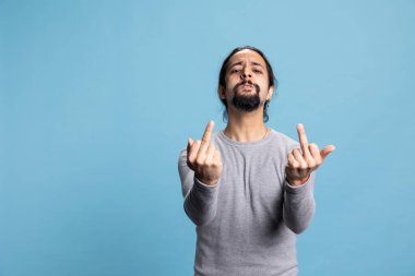 Hücum eden adam kameranın önünde orta parmağını gösteriyor ve kaba, agresif ve müstehcen bir işaretle öfkeli davranıyor. Kaba, kışkırtıcı ve zorba bir tavırla protesto eden genç adam..