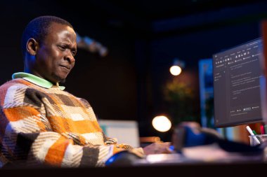 İçişleri Bakanlığı 'nda çalışan Afrikalı Amerikalı müteahhit iş yerindeki bilgisayarında kodlama yapıyor. Odaklanmış bilişim uzmanı apartmandan kontratlı iş yapıyor, masa başında kod satırları yazıyor..