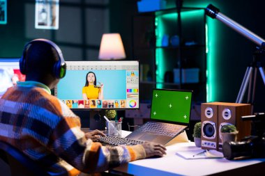 İzole edilmiş maket ekranın yanında gerekli dijital araçları kullanan erkek grafik sanatçısı, modern kurulumu sergileyen profesyonel tasarım çalışması. Gelişmiş fotoğraf düzenleme becerileri gösteren tasarımcı.