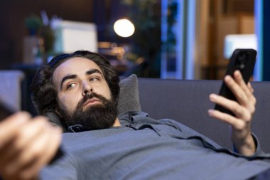 Yorgun bir adam kanallarda geziyor, oturma odasında aylak aylak dolaşırken haber izliyor ve arkadaşlarına mesaj atıyor. Tv istasyonunu seçmek için uzaktan kumanda kullanan ve cep telefonu kullanan kişi