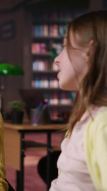 Dikey Video Tatlı Arkadaşlar ve sınıf arkadaşları ödevlerini bitirdikten sonra kucaklaşıyorlar, liseli kızlar kütüphanedeki arkadaşlıklarından memnunlar. Sevimli, neşeli, kucaklaşan gençler.