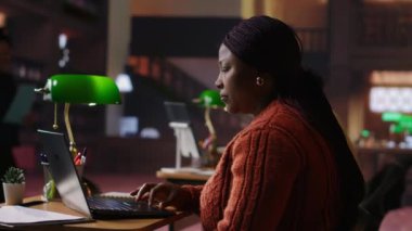 Huzurlu bir halk kütüphanesinde çalışan Afrikalı Amerikalı kütüphanecinin portresi öğrencilere rehberlik ve akademik uzmanlık sunuyor. Kadın eğitimsel kişisel materyalleri yönetiyor. Kamera B.