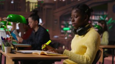 Kütüphanedeki genç kız çalışma oturumu için ilgili cümleleri vurguluyor, sınav için notlardaki paragrafları işaretliyor. Flüoresan bir kalemi çalışma tekniği olarak kullanmak. Kamera B.