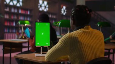 Afrikalı Amerikalı liseli bir kız kütüphanede kroma anahtarının yanına notlar yazıyor ve bir okul projesi üzerinde çalışıyor. Öğrenci dersler ve dersler için hazırlanıyor. Kamera B.