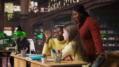 İlkokul öğrencileri ve öğretmenleri kütüphane masasından web kamerasıyla diğer sınıf arkadaşlarına bağlı bir çevrimiçi kursa katılıyorlar. Sanal Webinar tartışması. Kamera A.