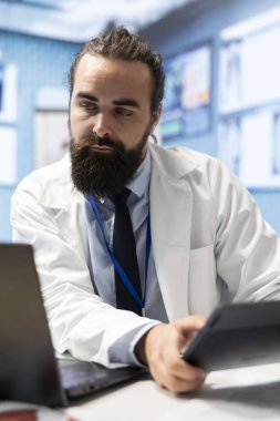 Sağlık kayıtları ve test sonuçlarıyla çalışan pratisyen hekimin ofisinde teşhisi bulmak için röntgen ve raporları incelemesi gerekiyor. Doktor hastalıkların önlenmesi ve tedavisi için araştırma yapıyor..