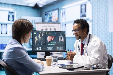 Doktor, kabinedeki kadın hastaya sağlık sigortası ve sağlık hizmetleri hakkında teşhis raporunu açıklıyor. Afrikalı Amerikalı doktor müşterilerine profesyonel danışmanlık ve geri bildirim yapıyor.