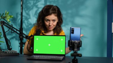 Kayıt cihazını kullanarak canlı yayını kaydedip kroma anahtar dizüstü bilgisayarı inceleyen bir etkili. Çevrimiçi şov sunucusu elektronik çekimleri çekiyor, izleyiciler için yeşil ekran defteri sunuyor, kamera A