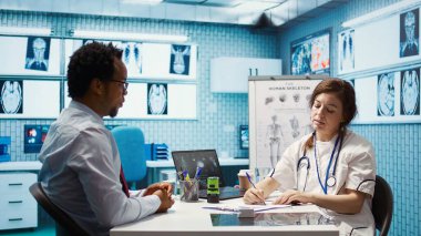 Doktor, tavsiye edilen tedavi ve sağlık için ilaveler içeren bir reçete yazıyor, hastaya talimatlar ve tıbbi tavsiyelerde bulunuyor. Sigorta için reçeteli ilaç yaz. Kamera B.