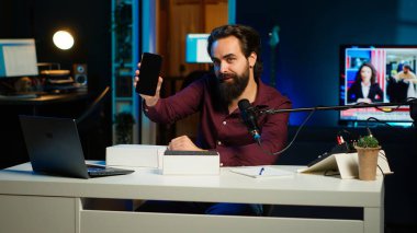 Teknik etken, yeni çıkan akıllı telefonun teknolojik incelemesini kaydediyor, paketini açıyor ve izleyicilere özelliklerini sunuyor. Abonelere telefon gösteren video blogcusu, Kamera A