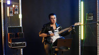 Annoyed female performer getting her vocals wrong during pre show rehearsal, doing musical warm up at practice session in the studio. Grunge rock star does performance prep. Camera B. clipart