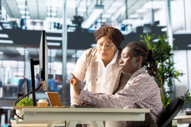 Genç çalışan ve yönetici bir bilgisayar etrafında toplanarak idari görevleri daha hızlı çözmek için hedefleri tartıştılar ve çözümler geliştirdiler. İş hedefleri ve kilometre taşlarının hizalanması.
