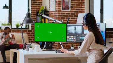 Renk derecelendirme yazılımının yanında krom anahtar fotokopi ekranı kullanarak yaratıcı bir proje video çekiminde çalışan kadın video düzenleyici. Ev işyeri verimliliği vurguluyor. Kamera B.