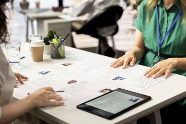 HR staff members using tablet to look at CVs and do background checks to potential job applicants. Headhunters use device to read resumes, attracting qualified candidates for vacant startup position clipart