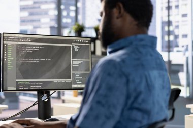 Sistem yöneticisi, hata oluşumunu en aza indirmek ve darboğazları tanımlamak için şirket yazılımını hata ayıklıyor. Afrika kökenli Amerikalı adam, hataları azaltmak için programlama dilinde temiz ve verimli kod yazıyor.