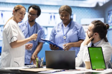 Muhtelif sağlık ekipleri fotokopi alanının yanındaki röntgenleri analiz eder ve tıbbi bir ofiste tedavi planlarını tartışırlar. Sigorta teşhisi için çalışan lisanslı sağlık uzmanlarından oluşan bir ekip..