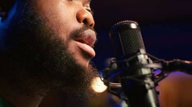 Artist records his voice on microphone in home studio singing a song composed by him. Skilled musician using recordings and lyrics to edit in post production, mixing and mastering session. Camera A. clipart